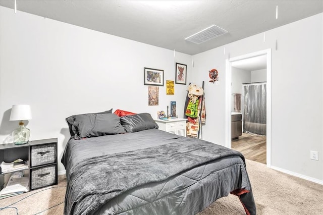 bedroom featuring ensuite bath and light colored carpet