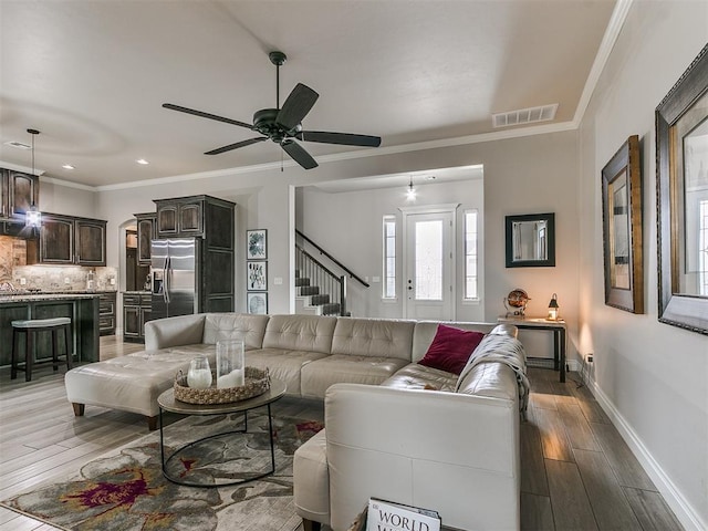 living room featuring hardwood / wood-style flooring, ornamental molding, and ceiling fan