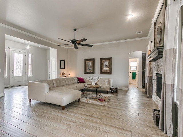 living room with crown molding, ceiling fan, a fireplace, and light hardwood / wood-style flooring