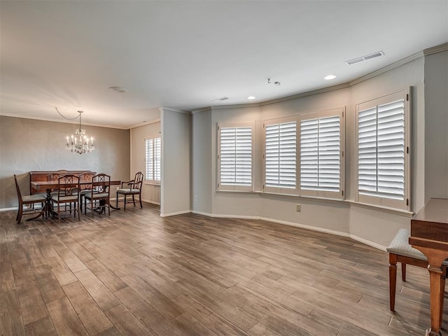 dining space with an inviting chandelier, ornamental molding, and wood-type flooring