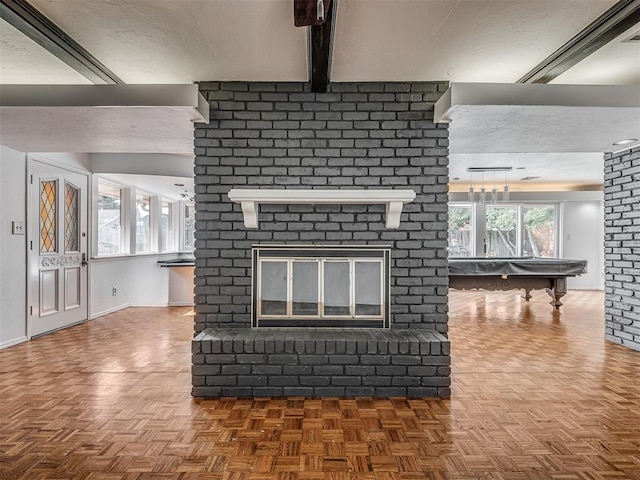 unfurnished living room with a brick fireplace, beam ceiling, and parquet flooring