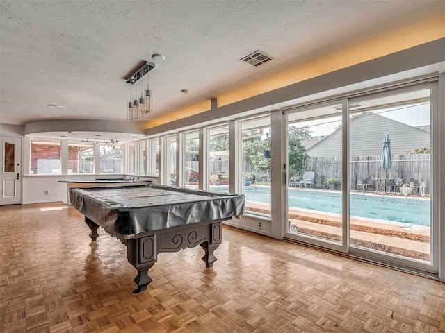 game room with light parquet flooring and a textured ceiling