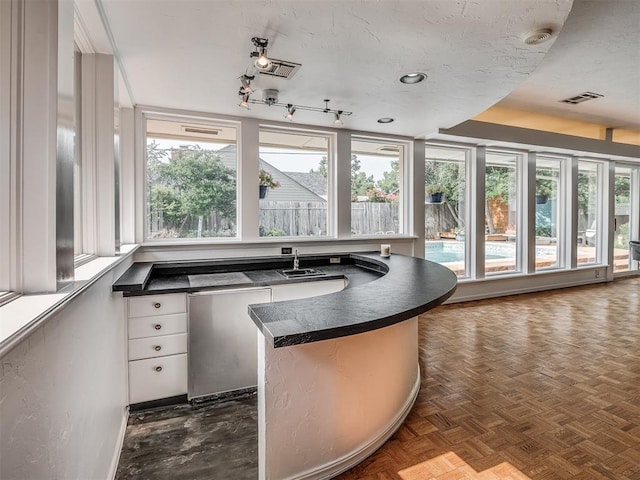 kitchen featuring plenty of natural light, sink, dark parquet floors, and white cabinets