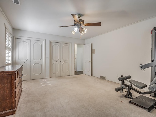 workout area featuring light colored carpet and ceiling fan