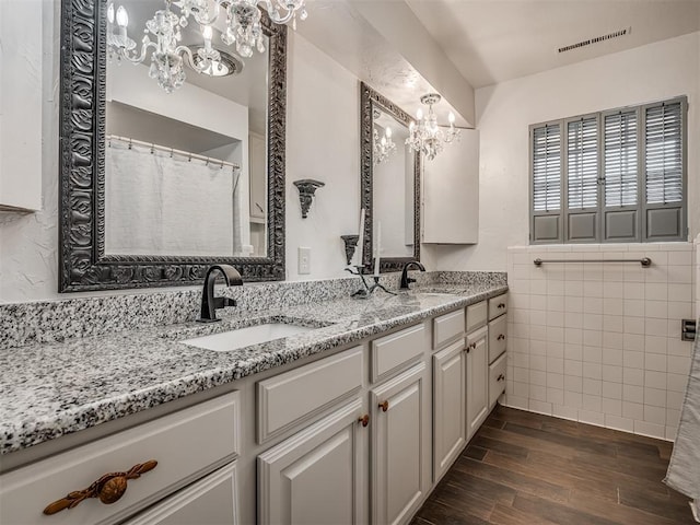 bathroom with vanity, hardwood / wood-style floors, tile walls, and a notable chandelier