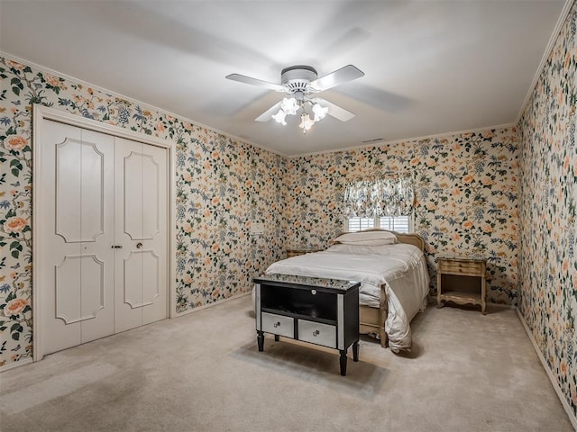 carpeted bedroom featuring ceiling fan, ornamental molding, and a closet