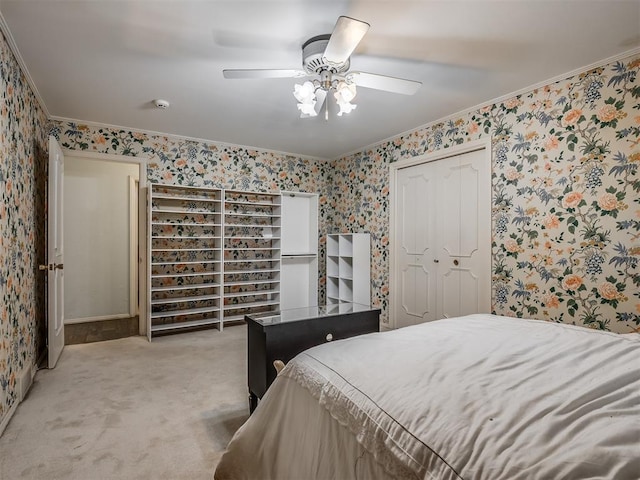 carpeted bedroom featuring crown molding, a closet, and ceiling fan