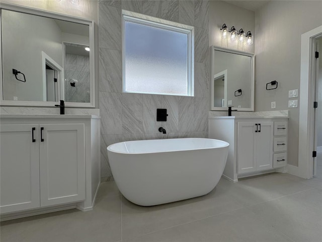 15521 Aparados Way, Edmond, OK 73013 - bathroom with a freestanding bath, two vanities, tile walls, and tile patterned floors
