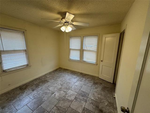 empty room with a wealth of natural light, a textured ceiling, and ceiling fan