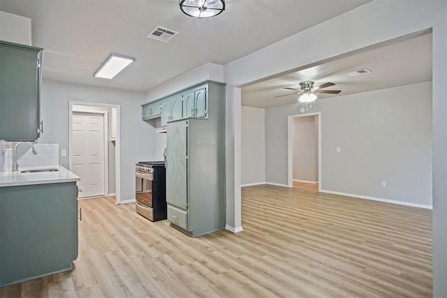 kitchen featuring refrigerator, sink, ceiling fan, gas range, and light wood-type flooring