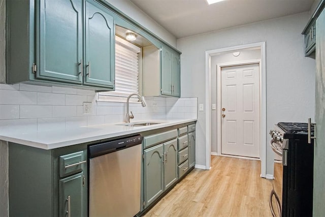 kitchen with sink, green cabinetry, stainless steel appliances, light hardwood / wood-style floors, and backsplash