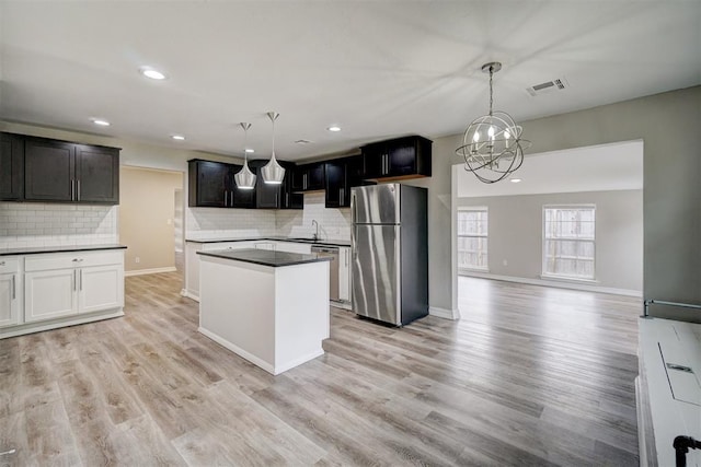 kitchen featuring pendant lighting, sink, backsplash, light hardwood / wood-style floors, and stainless steel appliances