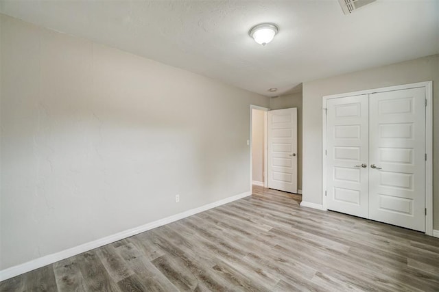 unfurnished bedroom featuring light hardwood / wood-style floors and a closet