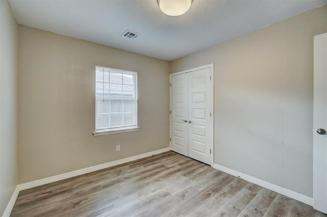 unfurnished bedroom featuring light wood-type flooring and a closet