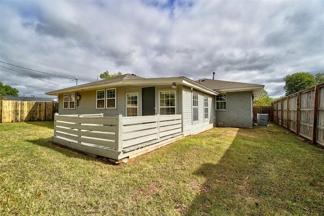 rear view of property with central AC and a lawn