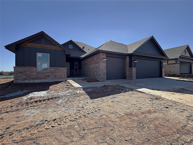 view of front facade with board and batten siding, brick siding, driveway, and an attached garage