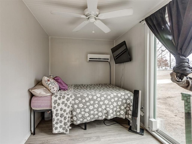 bedroom with light hardwood / wood-style flooring, a wall unit AC, and ceiling fan