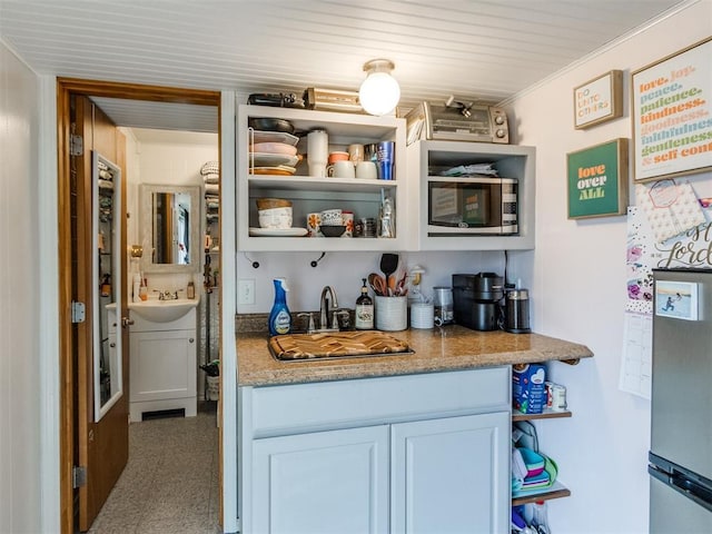 bar with sink, white cabinets, and light stone counters