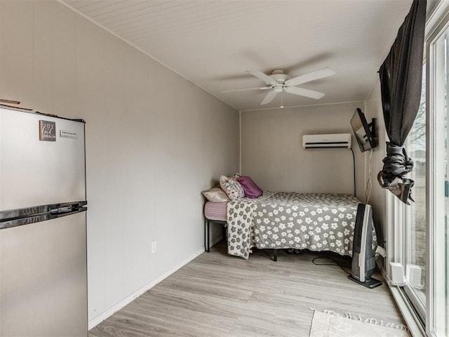 unfurnished bedroom featuring ceiling fan, stainless steel fridge, light wood-type flooring, and an AC wall unit