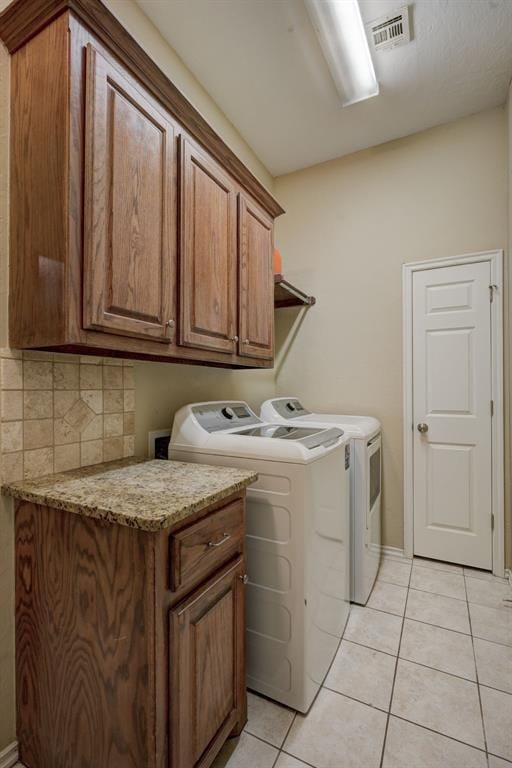 laundry area featuring independent washer and dryer, cabinets, and light tile patterned floors