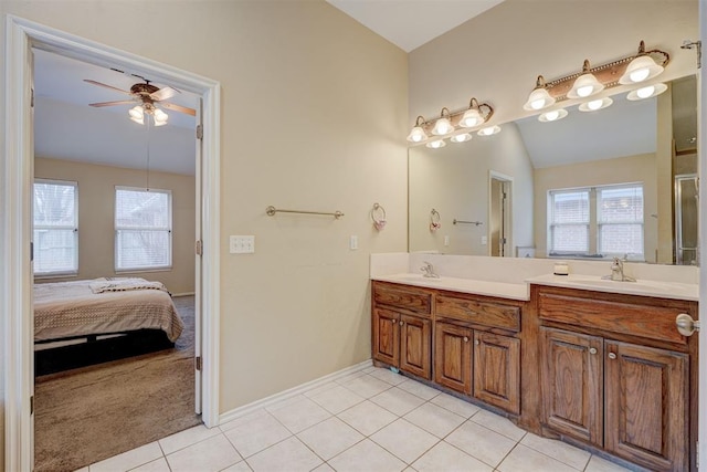 bathroom with tile patterned flooring, vaulted ceiling, a wealth of natural light, and vanity