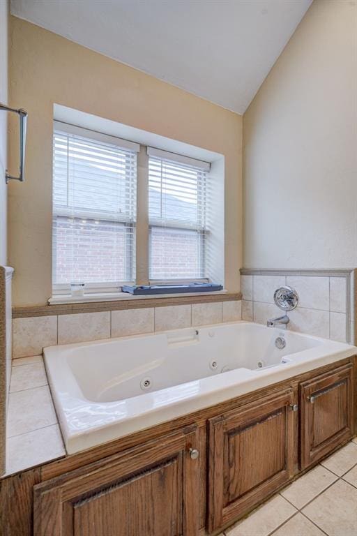 bathroom featuring tile patterned flooring, vaulted ceiling, and a tub