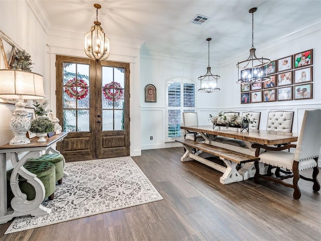 foyer entrance with crown molding, dark wood-type flooring, a notable chandelier, and french doors