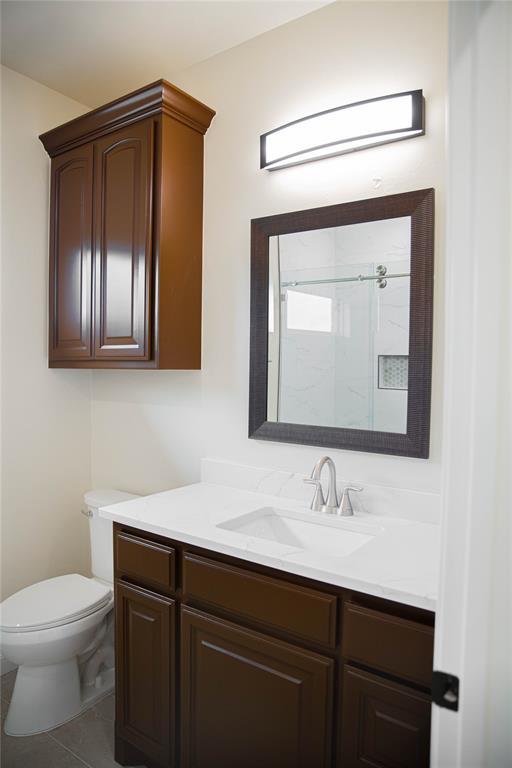 bathroom with vanity, toilet, tile patterned flooring, and a shower