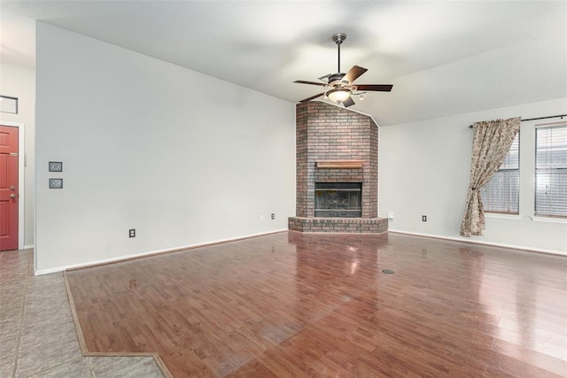 unfurnished living room featuring hardwood / wood-style flooring, vaulted ceiling, ceiling fan, and a fireplace