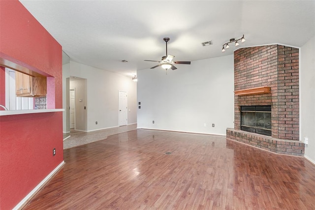 unfurnished living room with a brick fireplace, hardwood / wood-style floors, and ceiling fan