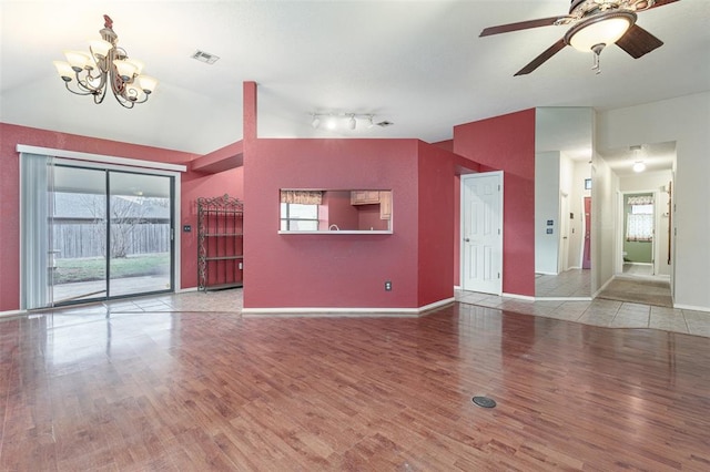 unfurnished living room with vaulted ceiling, ceiling fan with notable chandelier, and hardwood / wood-style floors