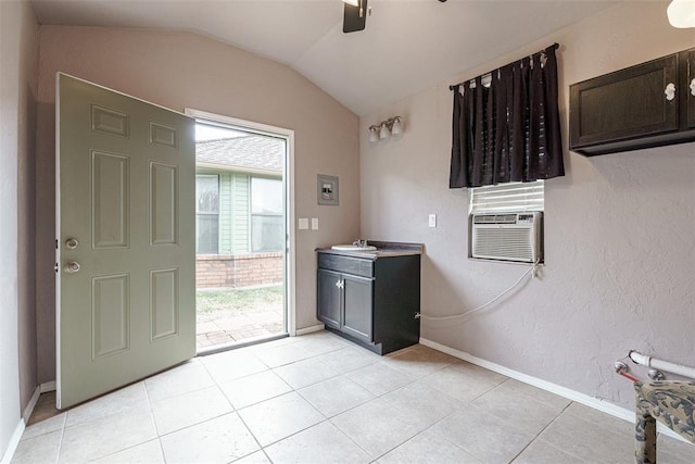 interior space featuring lofted ceiling, sink, light tile patterned floors, cooling unit, and ceiling fan