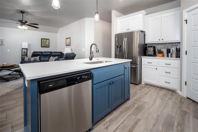 kitchen featuring appliances with stainless steel finishes, blue cabinets, an island with sink, sink, and white cabinets