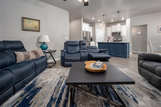 living room featuring sink, light hardwood / wood-style floors, and ceiling fan