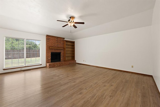 unfurnished living room featuring a brick fireplace, wood-type flooring, and ceiling fan