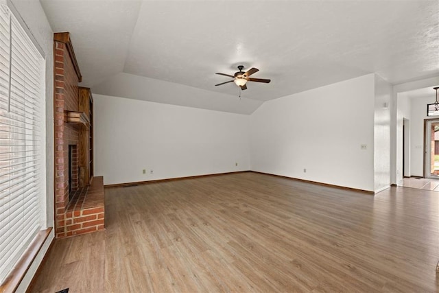 unfurnished living room featuring hardwood / wood-style flooring, ceiling fan, lofted ceiling, and a fireplace