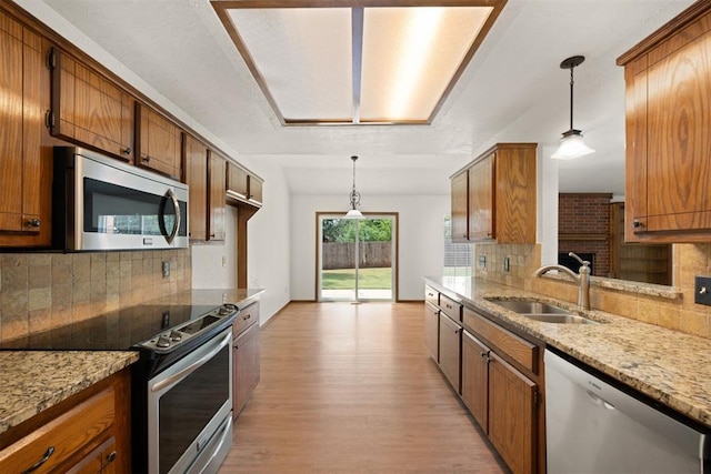 kitchen featuring pendant lighting, stainless steel appliances, sink, and light wood-type flooring