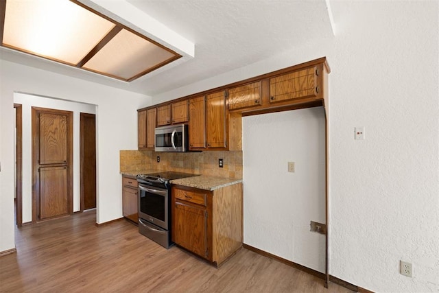 kitchen featuring stainless steel appliances, tasteful backsplash, light stone countertops, and dark hardwood / wood-style flooring