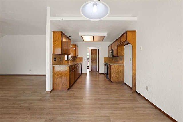 kitchen with backsplash, light hardwood / wood-style floors, sink, and appliances with stainless steel finishes