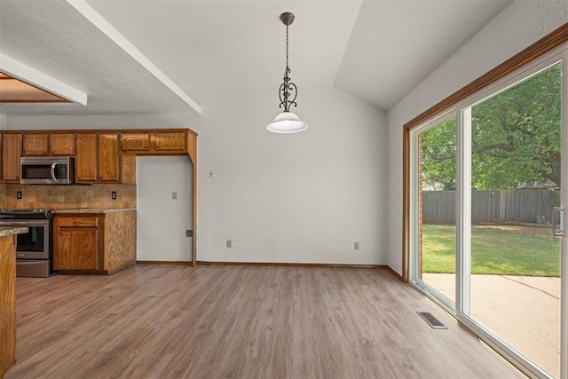 kitchen with tasteful backsplash, vaulted ceiling, hanging light fixtures, stainless steel appliances, and light hardwood / wood-style floors