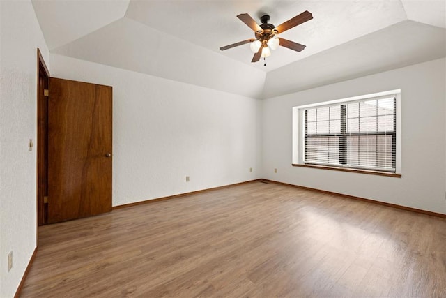 empty room with lofted ceiling, wood-type flooring, and ceiling fan