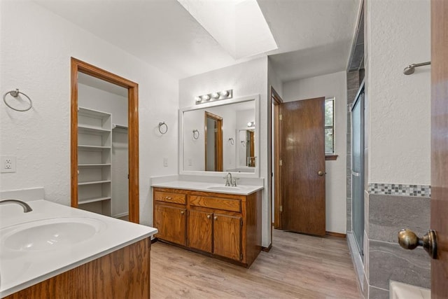 bathroom featuring vanity, a skylight, wood-type flooring, and a shower with shower door