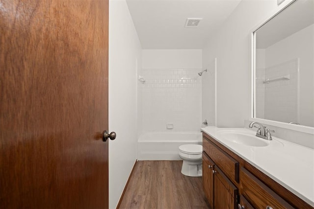 full bathroom with tiled shower / bath, vanity, toilet, and hardwood / wood-style floors