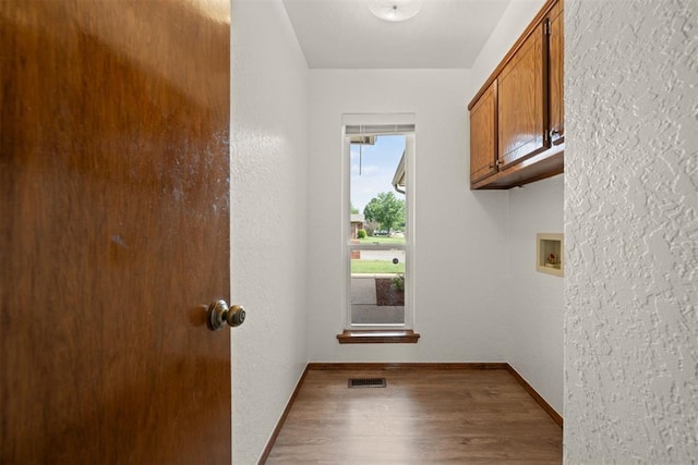 clothes washing area featuring hookup for a washing machine, hardwood / wood-style flooring, and cabinets