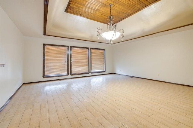 empty room featuring wood ceiling, a tray ceiling, and light wood-type flooring