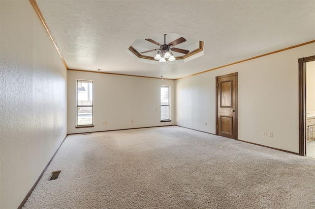 carpeted spare room with crown molding, a textured ceiling, ceiling fan, and a tray ceiling