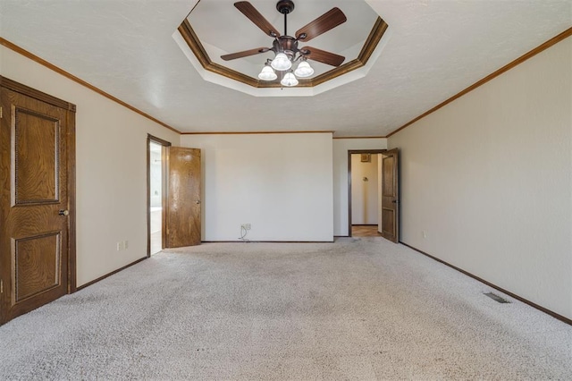 unfurnished bedroom featuring ceiling fan, ornamental molding, a tray ceiling, and light carpet