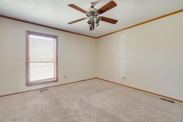 spare room with ceiling fan, ornamental molding, carpet flooring, and a textured ceiling