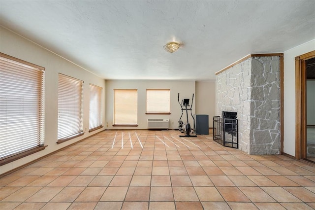 unfurnished living room with a stone fireplace, a healthy amount of sunlight, and light tile patterned floors