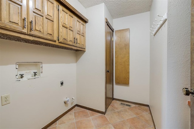 laundry area with light tile patterned floors, hookup for a washing machine, cabinets, a textured ceiling, and hookup for an electric dryer